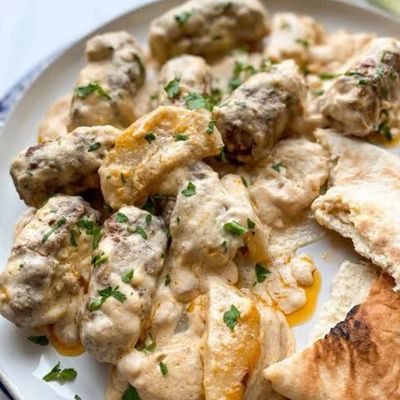 Kufta de vită coaptă cu cartofi și ceapă, acoperită cu sos de tahini